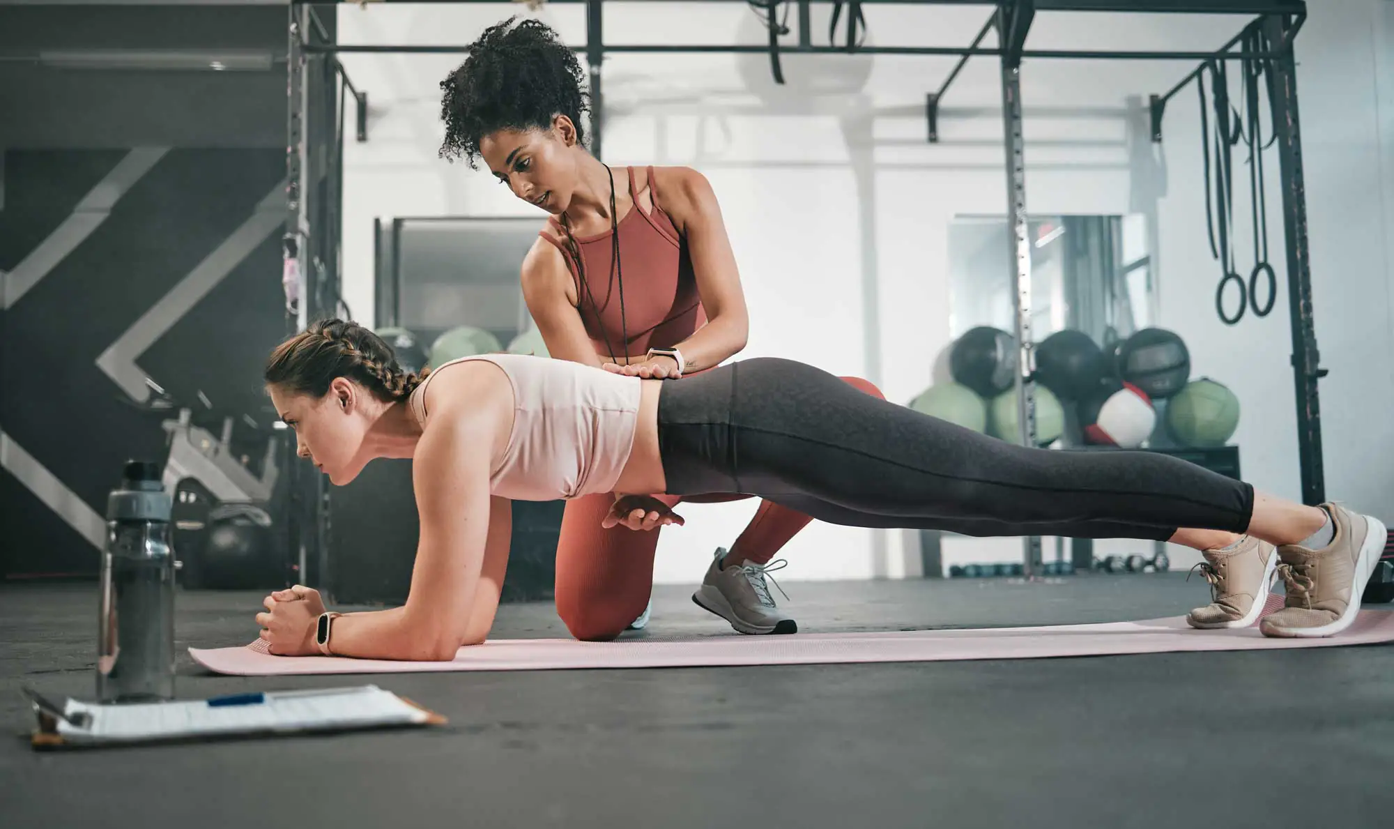 itness, plank or personal trainer at gym with woman for training, exercise or workout at health club. Women, focus or healthy sports athlete exercising with coach for progress, support or motivation